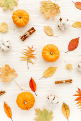 Orange pumpkins, cotton and dry leaves on white background. Flat lay, top view.  Autumn background. 