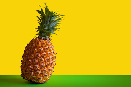 Beautiful ripe pineapple on a green table against the background of a yellow wall. Template for packaging or advertising of exotic fruit or juice. Clipart for the designer. Copy space.