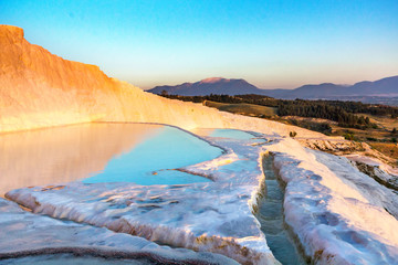 Pools of Pamukkale in Turkey in sunset, contains hot springs and travertines, terraces of carbonate minerals left by the flowing water, UNESCO World Heritage Site