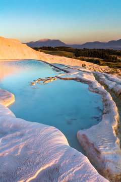 Pools of Pamukkale in Turkey in sunset, contains hot springs and travertines, terraces of carbonate minerals left by the flowing water, UNESCO World Heritage Site