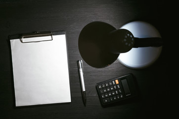 Tax calculation mock up. Payment on account. Blank document page, lamp and calculator on the black table background.