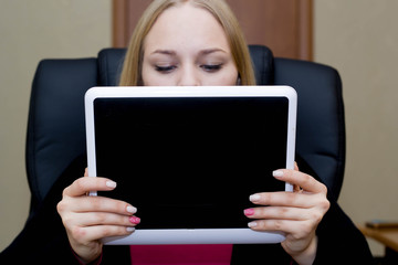 A girl holds in her hands and uses a tablet computer close up.