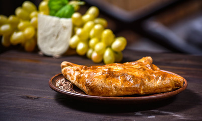 Traditional bread pita or khachapuri on the table with herbs. Homemade baking recipe.