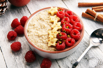 Bowl of oatmeal porridge with banana, raspberries coconut and caramel sauce on rustic table, hot and healthy food for Breakfast