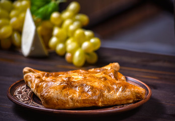 Traditional bread pita or khachapuri on the table with herbs. Homemade baking recipe.