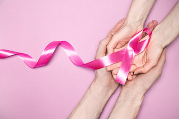 Obraz na płótnie Canvas Pink ribbon in hand. Breast cancer symbol.