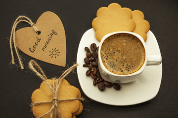Black coffee with coffee beans and cookies on a dark background. Breakfast, top view.