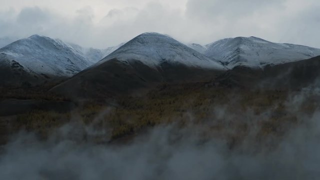 Aerial drone shot of forest valley and mountain range through low cloud. Earth nature beauty winter mountain range aerial flight epic scale Inspirational.