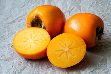 Whole and half of fresh ripe persimmons. Japanese persimmon (Diospyros kaki)