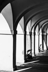 Old historical arcade with benches in old town. Black and white image.