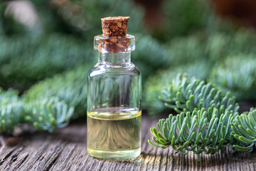 A bottle of fir essential oil with fir branches