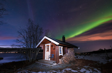 The polar arctic Northern lights aurora borealis sky star in Scandinavia Norway Tromso in the farm winter forest  snow mountains  with wooden sauna