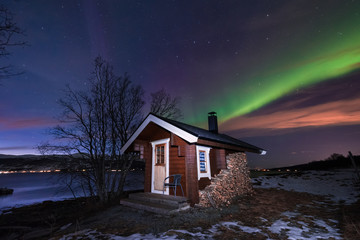 The polar arctic Northern lights aurora borealis sky star in Scandinavia Norway Tromso in the farm winter forest  snow mountains  with wooden sauna