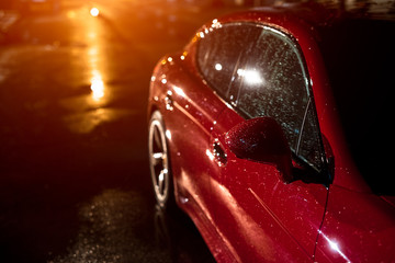 Back view of red modern sport car, after rain in night city.