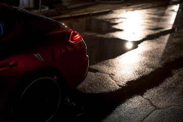 Back view of red modern sport car, after rain in night city.
