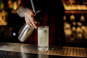Fototapeta na wymiar Barman adding soda water to a lemonade cocktail