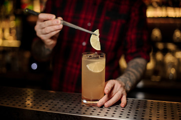 Fototapeta na wymiar Barman decorating alcoholic lemonade with lemon slices