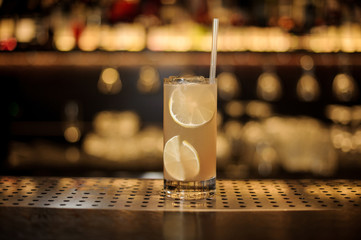 Glass of fresh alcoholic orange cocktail with juicy lime slices and straw