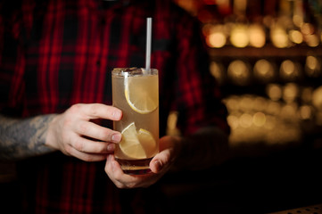 Bartender holding a glass of fresh alcoholic orange cocktail