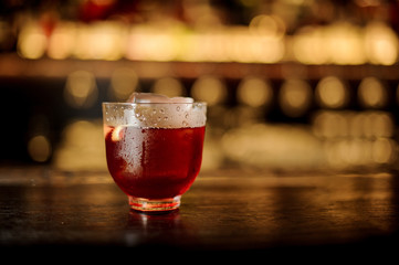 Glass with fresh and strong whiskey cocktail against the bar lights
