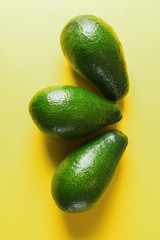 Traditional mexican snack - Green raw fresh avocado. On the yellow background