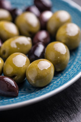 Green and dark olives on a blue greek plate.