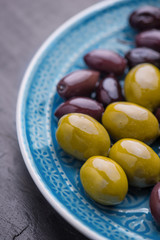 Green and dark olives on a blue greek plate.