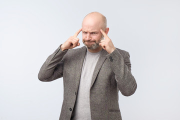 Angry tired european man gesturing with his finger against temple trying to remember something.