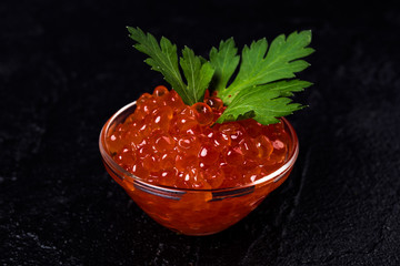 Red caviar in  bowl, dark background