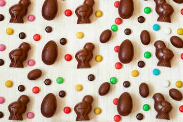 Easter background with chocolate candies in the shape of rabbit, chicken, eggs and sweets. Chocolate easter eggs. Flat lay. View from above