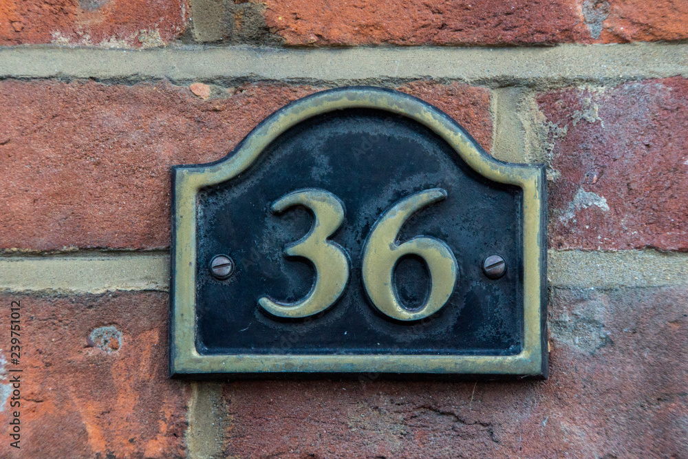 Wall mural The house number 36 in brass on a red brick wall,