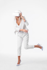 Blond woman in white suite with virtual reality goggles. Studio shot on white background