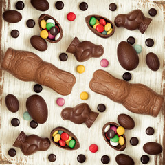 Easter background with chocolate candies in the shape of rabbit, chicken, eggs and sweets. Chocolate easter eggs. Flat lay. View from above