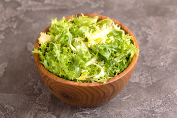 Fresh frisee salad in wooden bowl. Healthy food