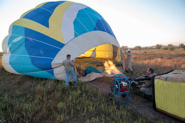 People inflate a balloon, men inflate a hot air balloon. The balloon begins to rise into the air. Flame burners for aerostat.