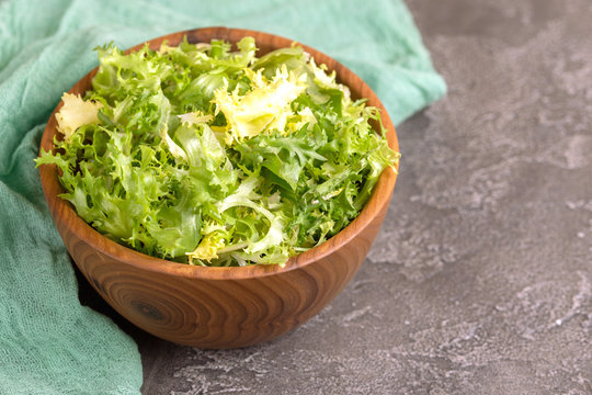 Fresh frisee salad in wooden bowl. Healthy food