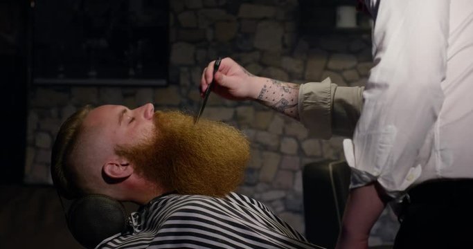 Barber with comb long beard male client in Barbershop slow motion