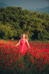 Fototapeta na wymiar Beautiful woman enjoying nice day in poppy field, wearing pink dress