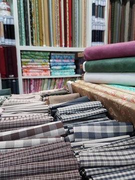 Rolls of fabric and checkered textiles and other designs and colors in a factory shop, store or bazaar