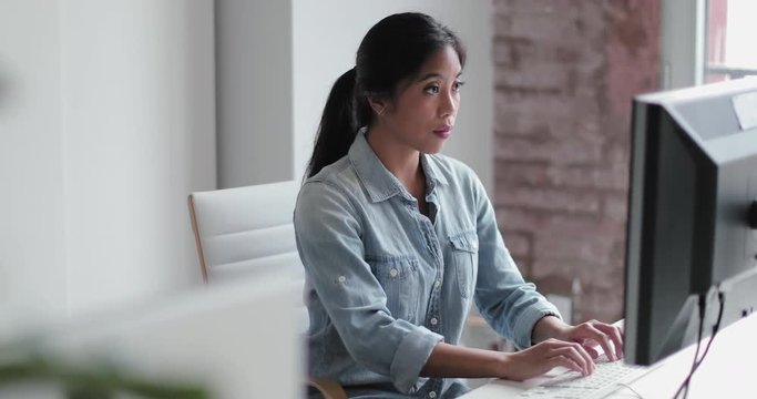 Young adult female working in an office on a desktop computer