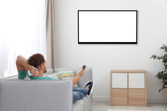 Young Man Watching TV On Sofa At Home. Mockup For Design