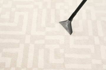 Removing dirt from carpet with vacuum cleaner indoors, closeup. Space for text