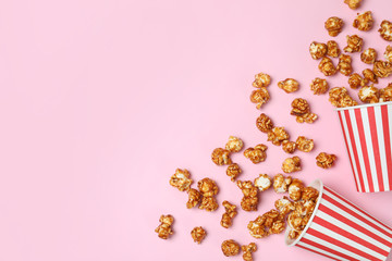 Overturned paper cups with caramel popcorn on color background, top view. Space for text