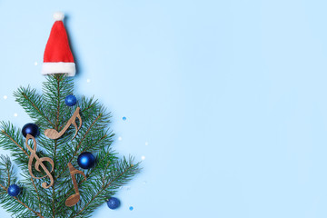 Flat lay composition with Christmas tree branch, Santa hat, wooden music notes and space for text...