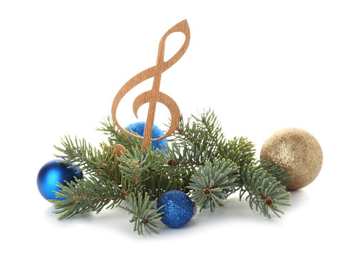 Composition with wooden treble clef, balls and fir tree branches on white background. Christmas music concept