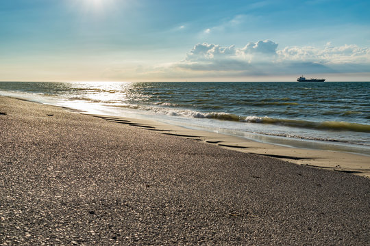 Nature, water, environment and paysage concept: view of the North Sea, ship in the background and clouds.