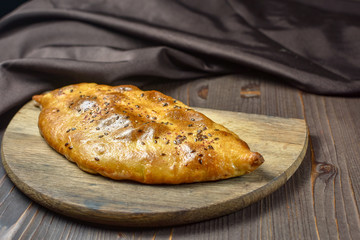 Traditional bread pita or khachapuri on the table with herbs. Homemade baking recipe.