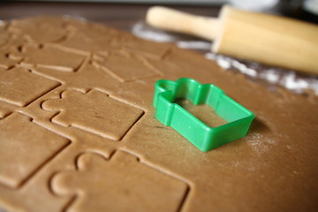 Pieczenie pierników - zbliżenie na formę zielony prezent wduszoną w ciasto piernikowe w tle...