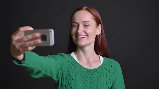 Closeup portrait of attractive caucasian female making selfies posing smiling and playing an ape happily