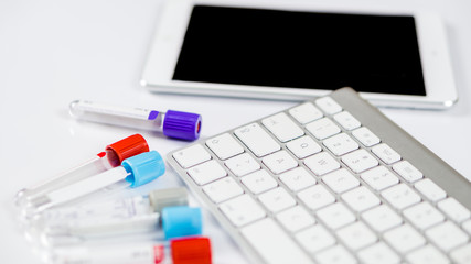 Medicine bottles for samples next to computer tablet and computer keyboard in medicine, closeup on white background